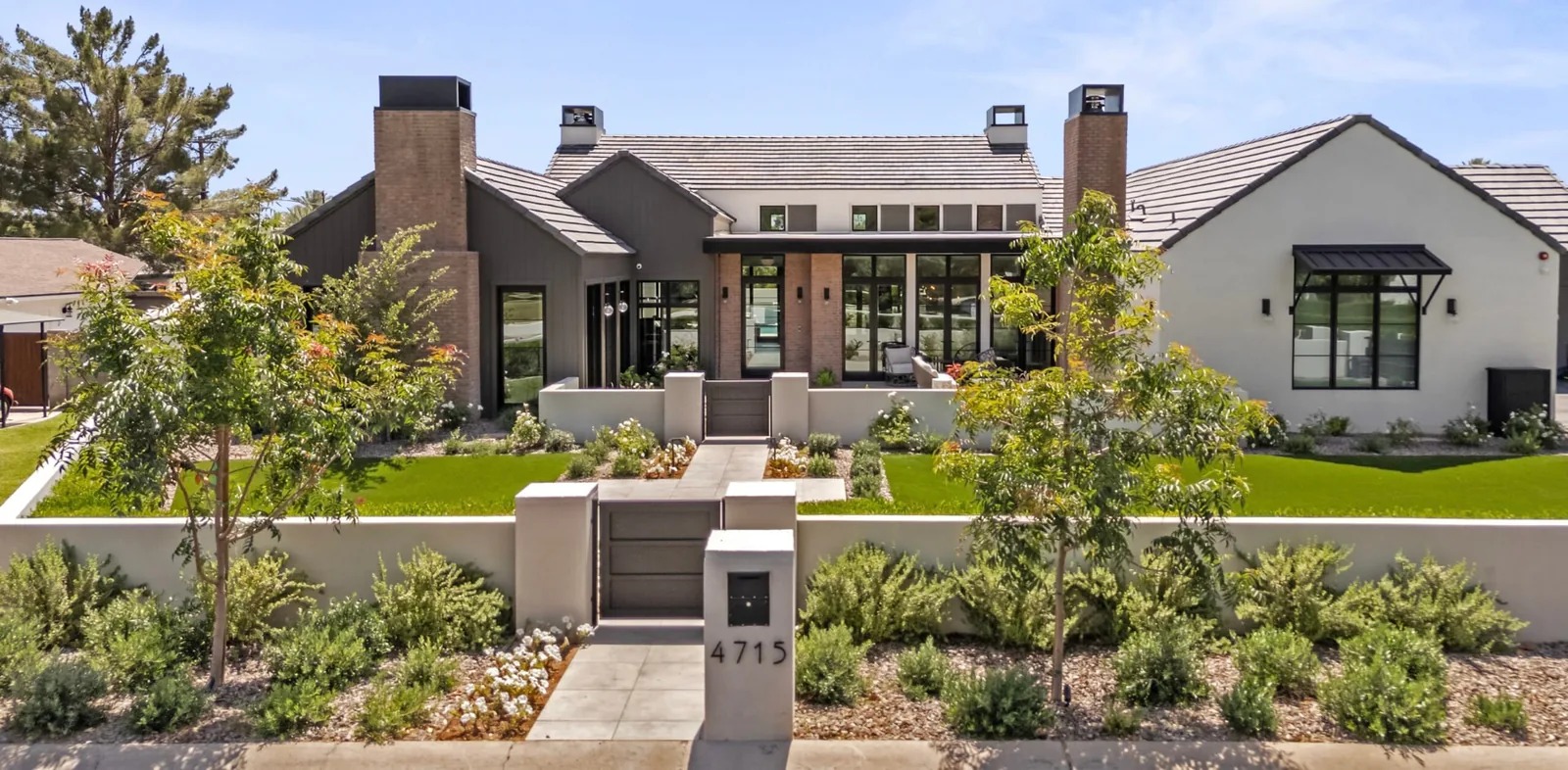 Completed modern luxury residence with landscaped front courtyard, gated walkway and contrasting stucco, brick and dark siding